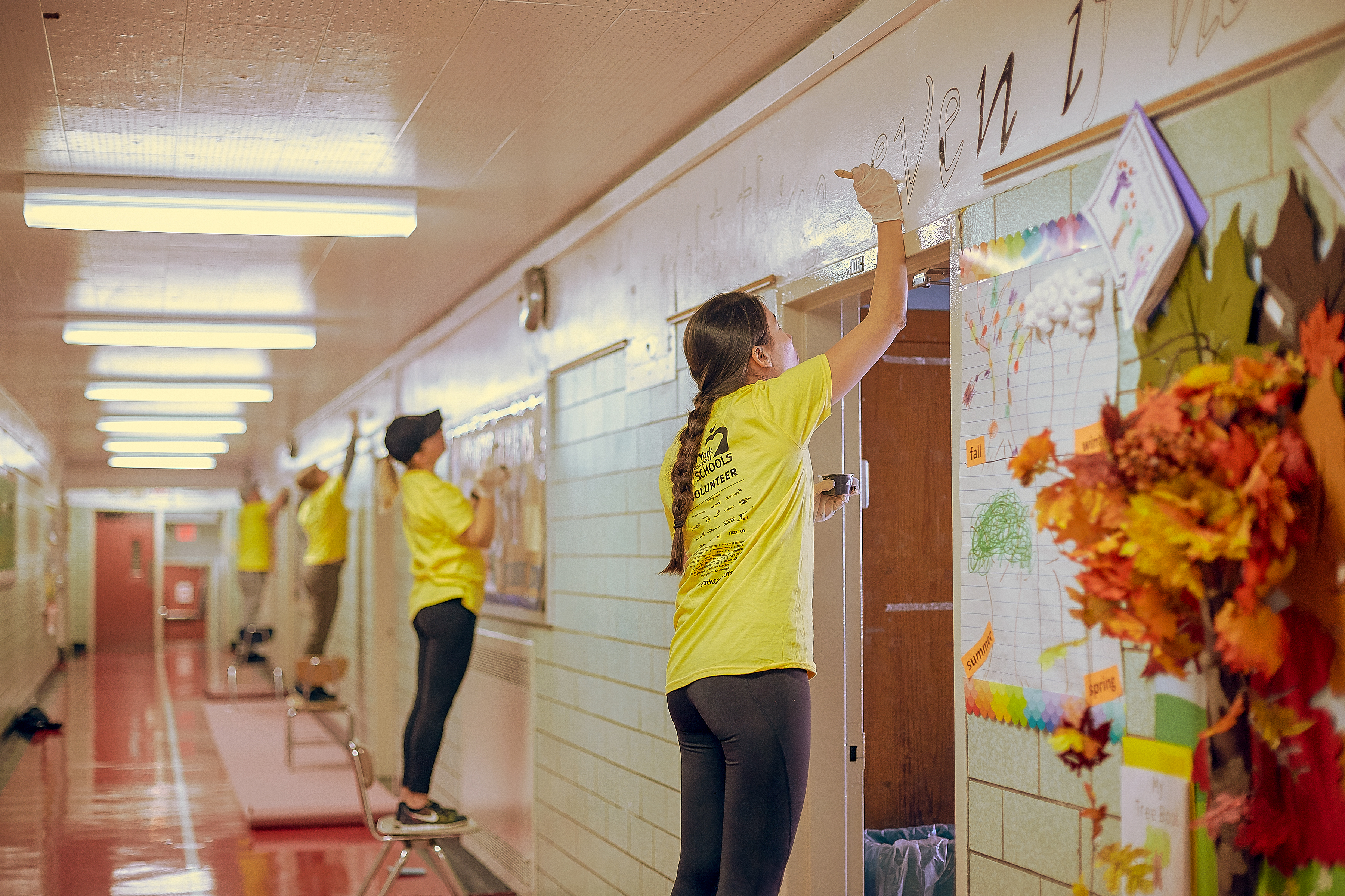 Four people in yellow shirts painting hallway