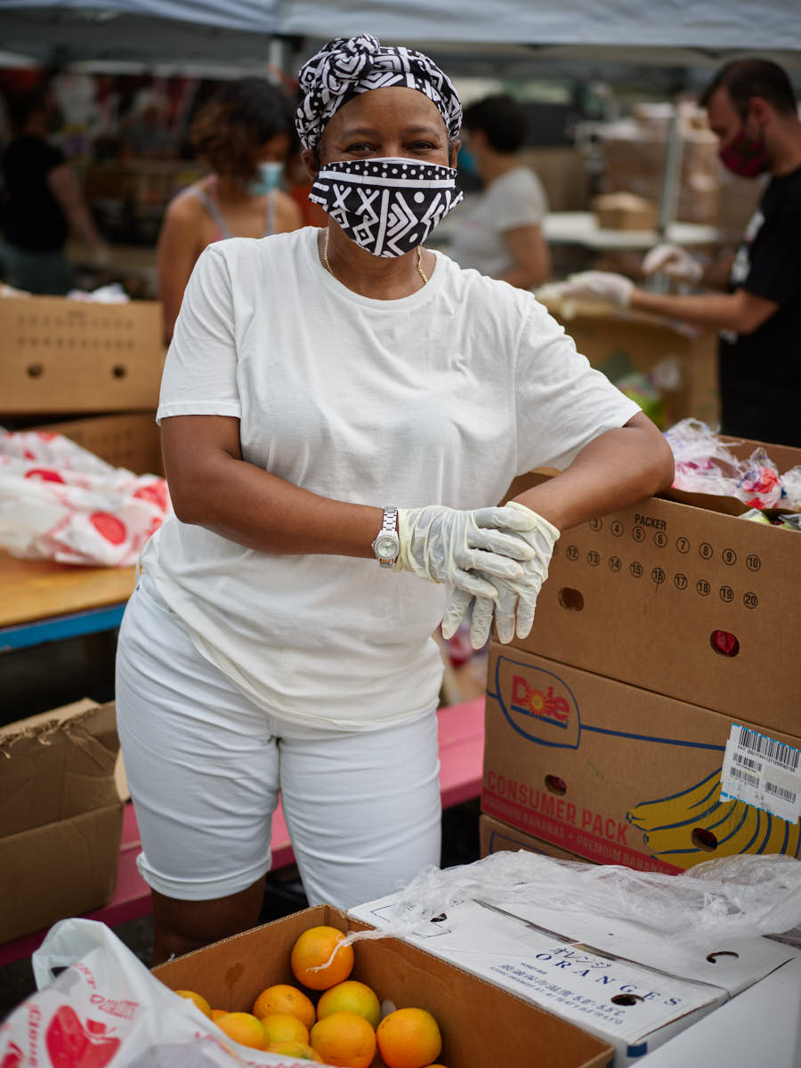 Woman wearing white t shirt and mask with boxes of food