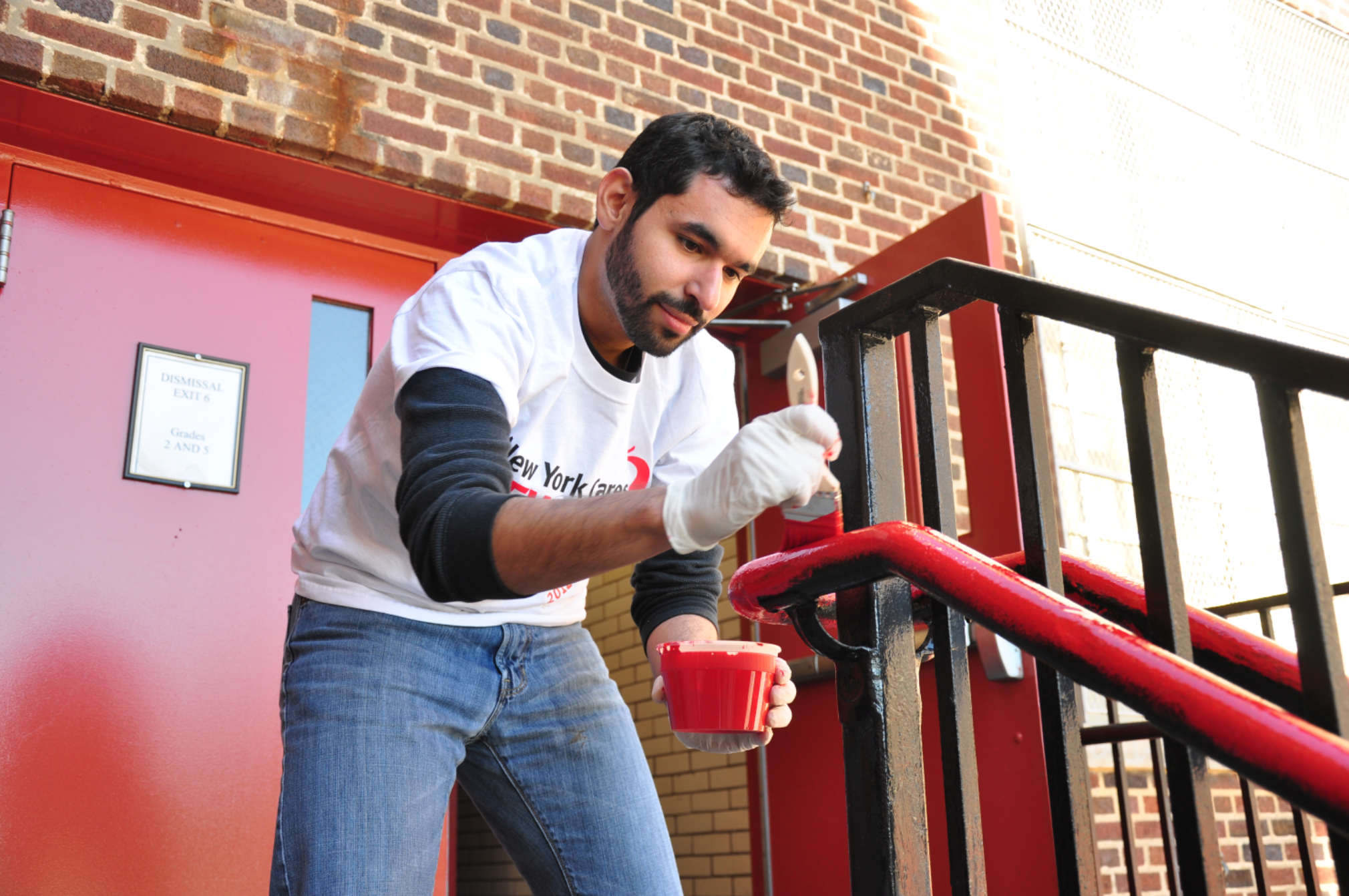 Man holding paint brush and red paint painting railing